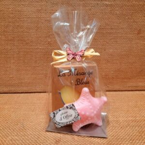 Sachet cadeau contenant un savon parfumé et un savon en forme d'étoile de mer de couleur rose, sur un fond en jute