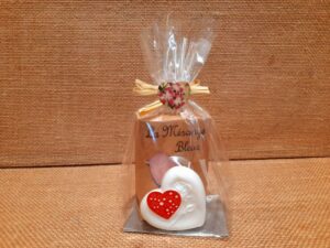 Sachet cadeau contenant un savon parfumé et un savon en forme de cœur de couleur blanc, sur un fond en jute