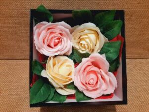 Vue intérieur d'un coffret cadeau avec 4 roses en savons, 2 de couleur rose pâle et 2 de couleur crème