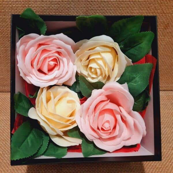 Vue intérieur d'un coffret cadeau avec 4 roses en savons, 2 de couleur rose pâle et 2 de couleur crème