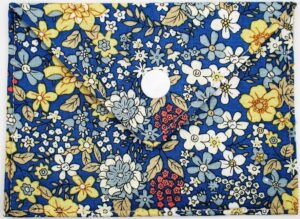 Pochette à savon Andrée, bleu nuit avec des motifs floraux blanc, jaune pâle et bleu clair, avec un bouton pression rond blanc