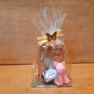 Sachet cadeau contenant un savon parfumé et un savon en forme de cochon de couleur rose, sur un fond en jute