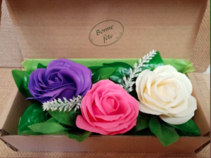 Coffret comprenant 3 savons en forme de roses de couleurs violet, rose et blanc