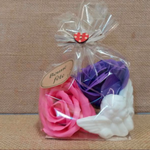 Sachet de 3 savons comprenant un savon fantaisie en forme d’ange parfumé au muguet et 2 savons en forme de roses (1 rose et 1 violet), sur un fond en jute