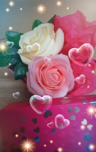 Boîte de couleur rose décorée de cœurs, contenant une un savon en forme de rose de couleur rose et un savon en forme de rose de couleur blanche